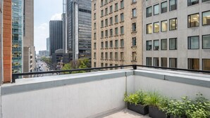 Un balcon offrant une vue sur la ville, avec des bâtiments modernes et un sol carrelé.