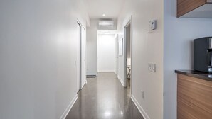 Un couloir étroit et bien éclairé, avec une armoire en bois sur le côté droit et une porte au fond.