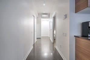 A narrow, well-lit hallway with a wooden cabinet on the right and a door at the end. - Historic Old Montreal Stay - Iconic Location (Montreal)