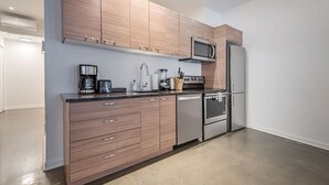 Une cuisine moderne avec des meubles en bois, des appareils en acier inoxydable et un plan de travail noir.