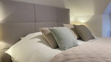 A neatly made bed with a headboard, pillows, and a blanket.