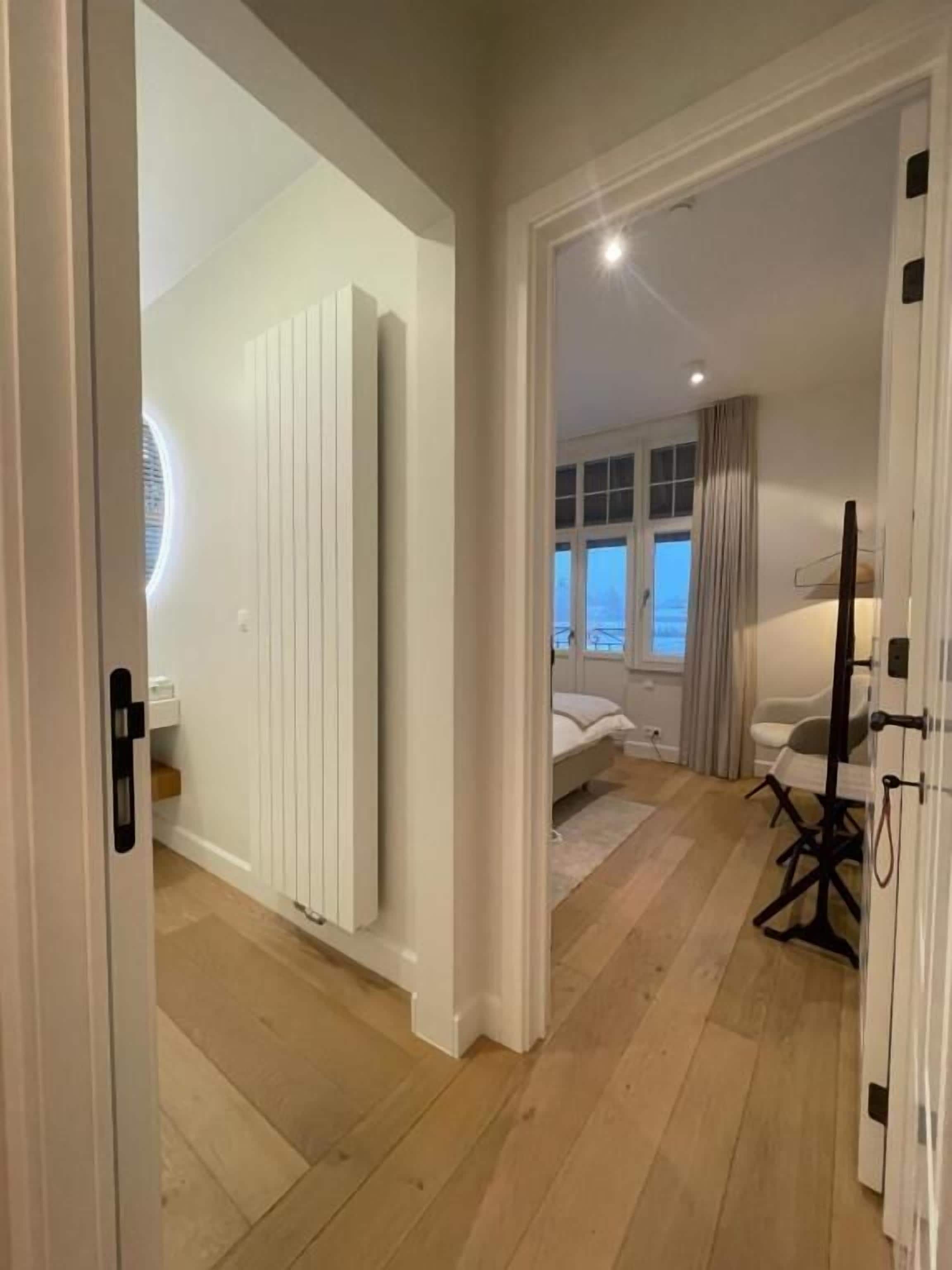 Ein modernes Schlafzimmer mit Bett, Heizkörper und Blick ins Freie.