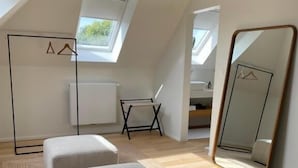 A modern loft bedroom with a sloped ceiling, a large mirror, and a skylight. - Villa Magnolia (Oostkamp)