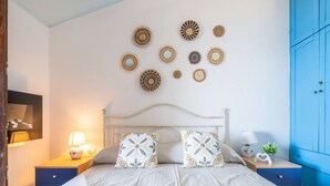 Una camera da letto con un letto, comodini, una lampada, un armadio blu e decorazioni a parete.