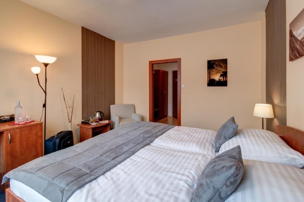 A hotel room with a bed, bedside tables, a lamp, a wardrobe, and a painting on the wall.