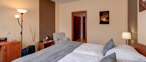 A hotel room with a bed, bedside tables, a lamp, a wardrobe, and a painting on the wall.