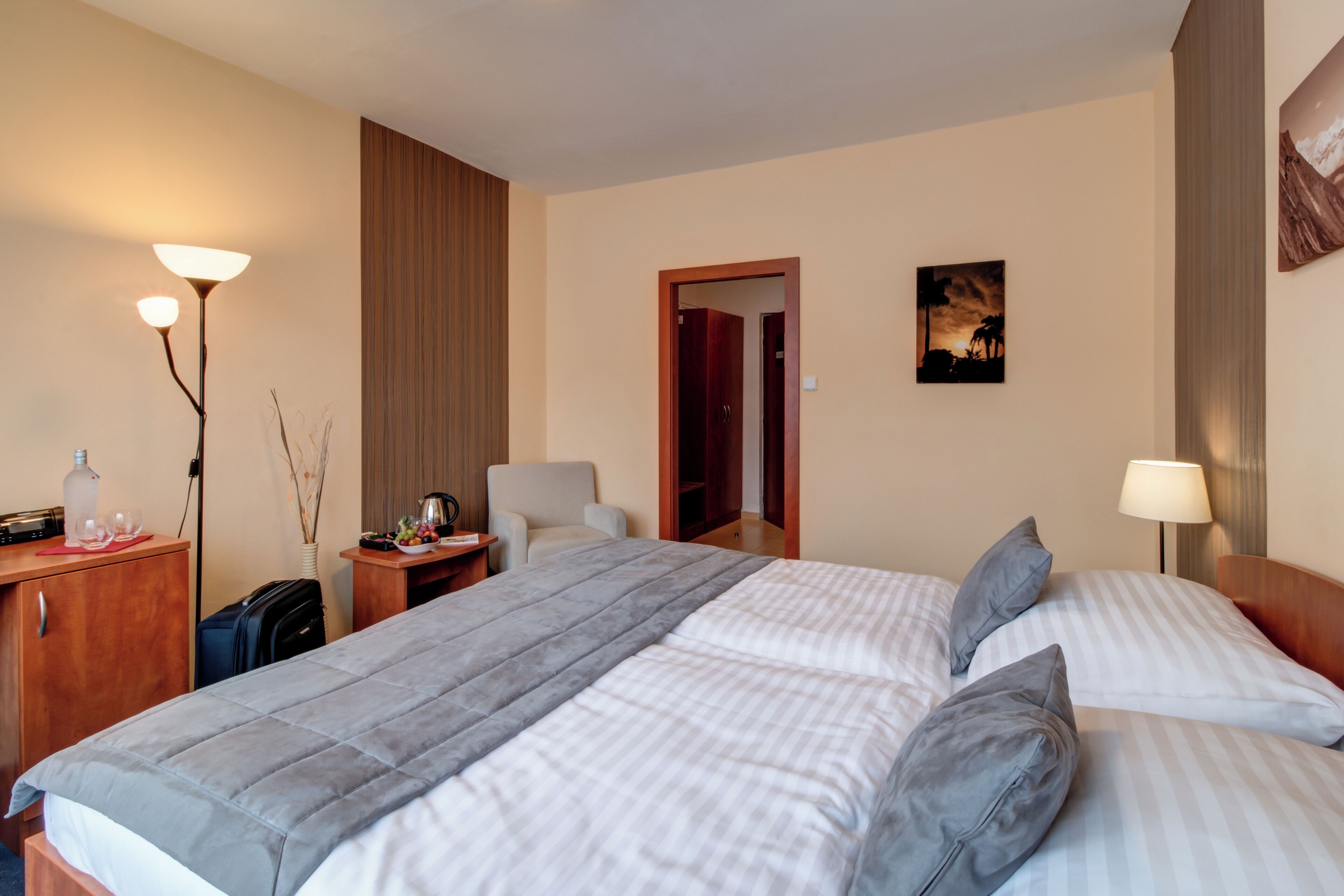 Ein Hotelzimmer mit Bett, Nachttischen, einer Lampe, einem Schreibtisch, einem Stuhl und einem Kleiderschrank.