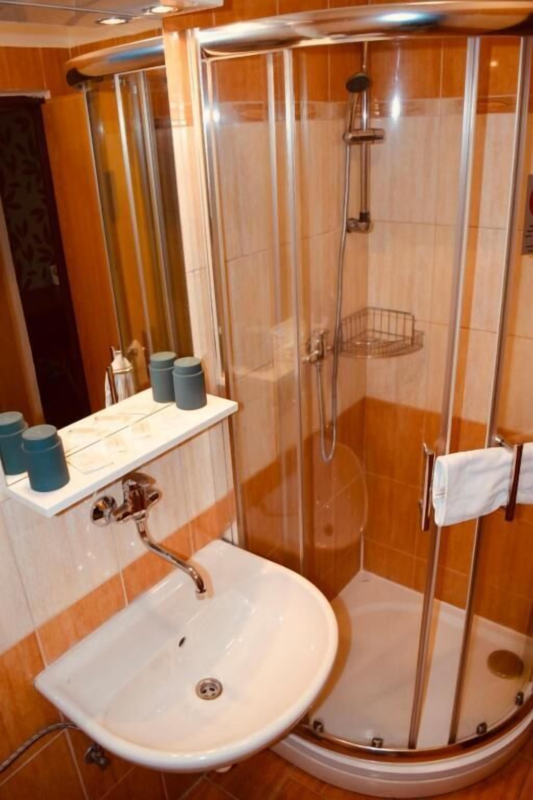 A bathroom with a glass-enclosed shower, a sink, and a mirror.