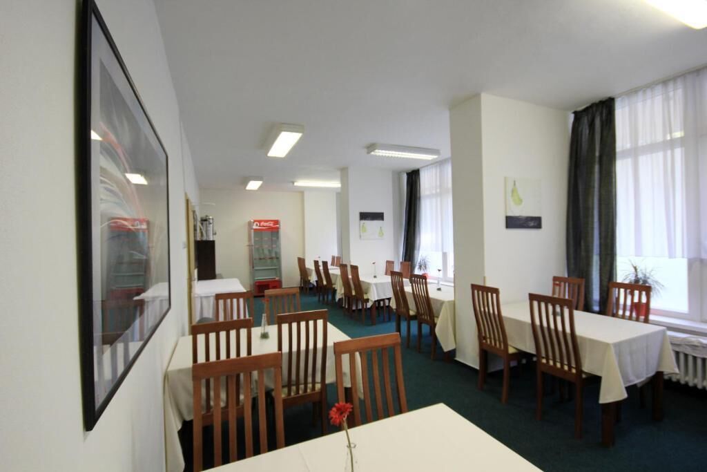 A dining area with multiple tables and chairs, a framed picture on the wall, and a window with curtains.