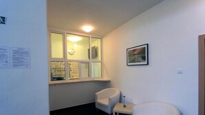 A small, well-lit room with a window, two white chairs, a small table, and a framed picture on the wall. - LC Hotel Ostrava (Ostrava)