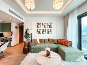 A modern living room with a green sectional sofa, a round coffee table, and abstract art on the wall. - Chic & Cozy 1BR in Heart of City Walk (Dubai)