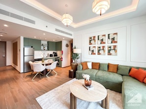 A modern living room with a green sofa, a round coffee table, and a dining area with a white table and chairs. - Chic & Cozy 1BR in Heart of City Walk (Dubai)