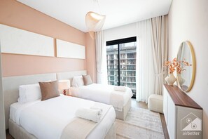 A hotel room with two beds, a large window with a city view, a mirror, and a desk with a vase of flowers. - Stylish City Walk 2BR Apt Balcony Iconic Views (Dubai)
