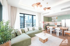 A modern living room with a sectional sofa, a dining area with a wooden table and chairs, and a kitchen in the background. - Stylish City Walk 2BR Apt Balcony Iconic Views (Dubai)