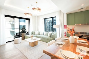 A modern living room with a green sofa, wooden coffee table, and dining area set for six. - Stylish City Walk 2BR Apt Balcony Iconic Views (Dubai)