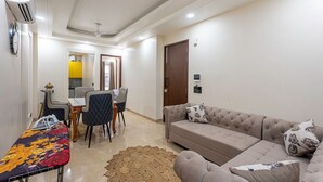 Ein Wohnzimmer mit einer Couch, einem Esstisch mit Stühlen, einem gemusterten Teppich und einem Deckenventilator.