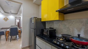 Eine moderne Küche mit einem schwarzen Kühlschrank, einem Herd mit einem roten Topf und gelben Schränken.