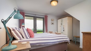 Ein Schlafzimmer mit einem Bett, einem Schreibtisch, einem Stuhl, einem Kleiderschrank und einem Fenster.