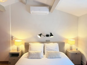 Ein Hotelzimmer mit einem Bett, zwei Nachttischlampen, einer Klimaanlage und einem Nachttisch mit Lampe.
