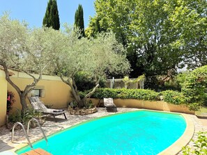 A swimming pool with lounge chairs, a stone wall, and trees. - Peps Pink Flamingos, 2 bedrooms, pool, near downtown (Saint-Rémy-de-Provence)