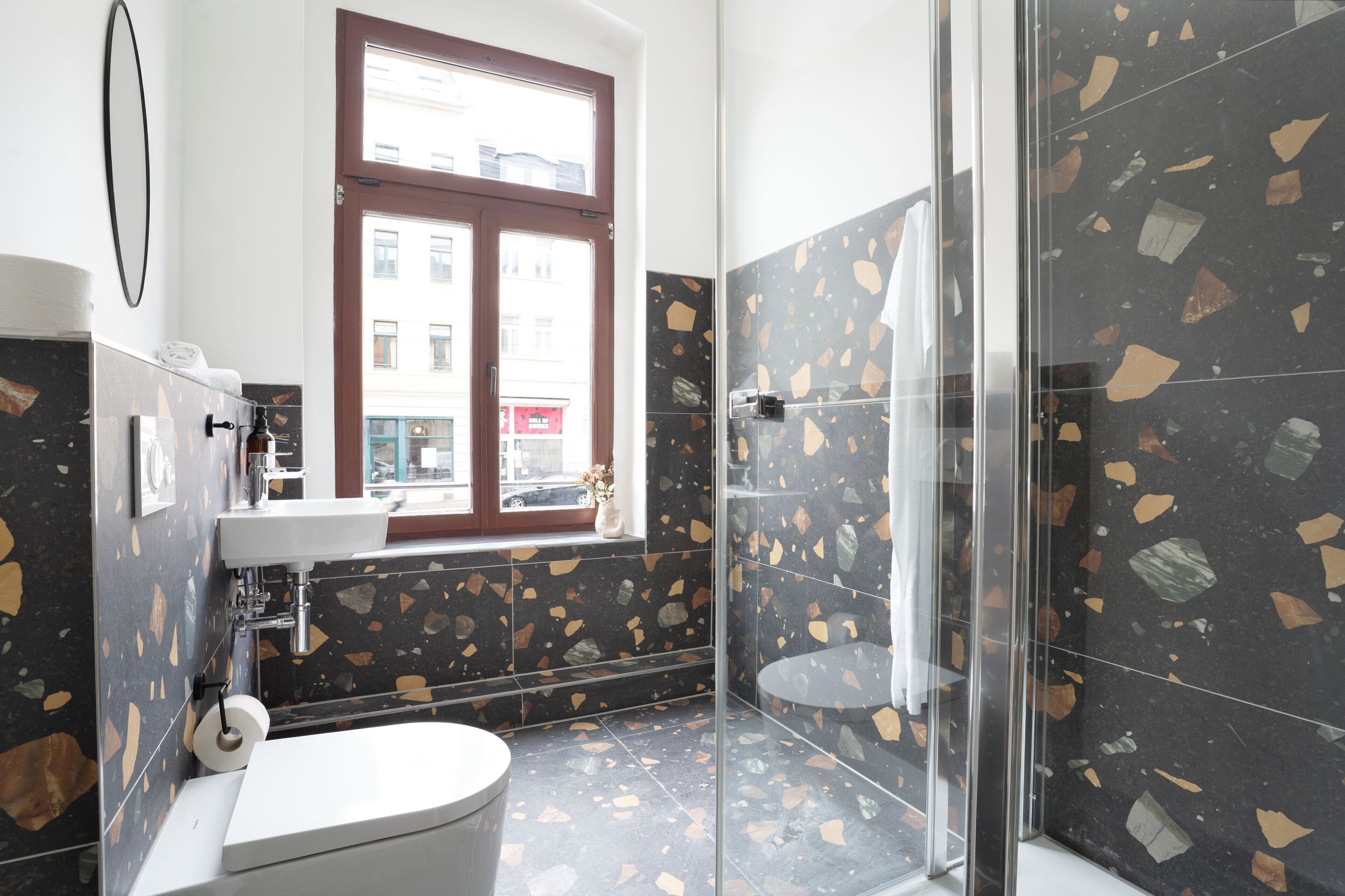A bathroom with a toilet, sink, and glass shower enclosure.