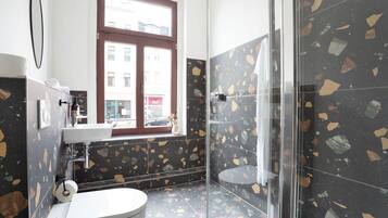 A bathroom with a toilet, sink, and glass shower enclosure.