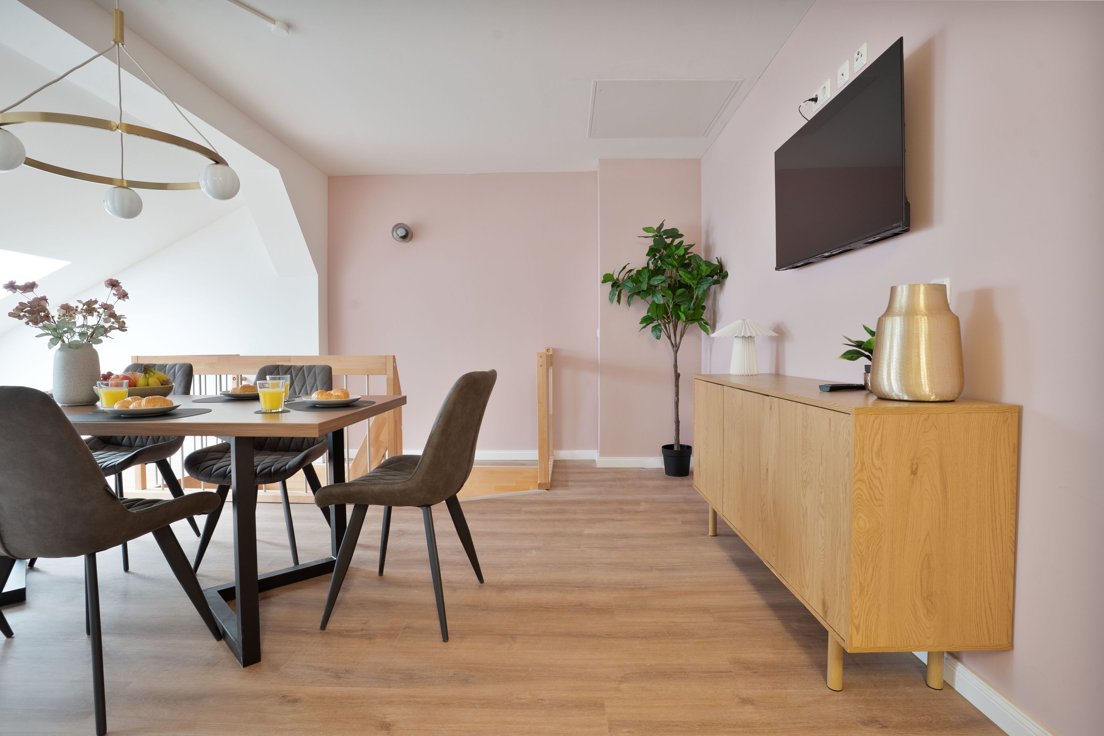 Un espace repas moderne avec une table en bois, des chaises et un téléviseur fixé au mur.