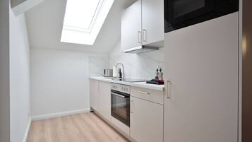 Een moderne keuken met witte kasten, een ingebouwde oven en een magnetron.