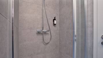 A modern shower with a handheld showerhead and a wall-mounted soap dispenser.