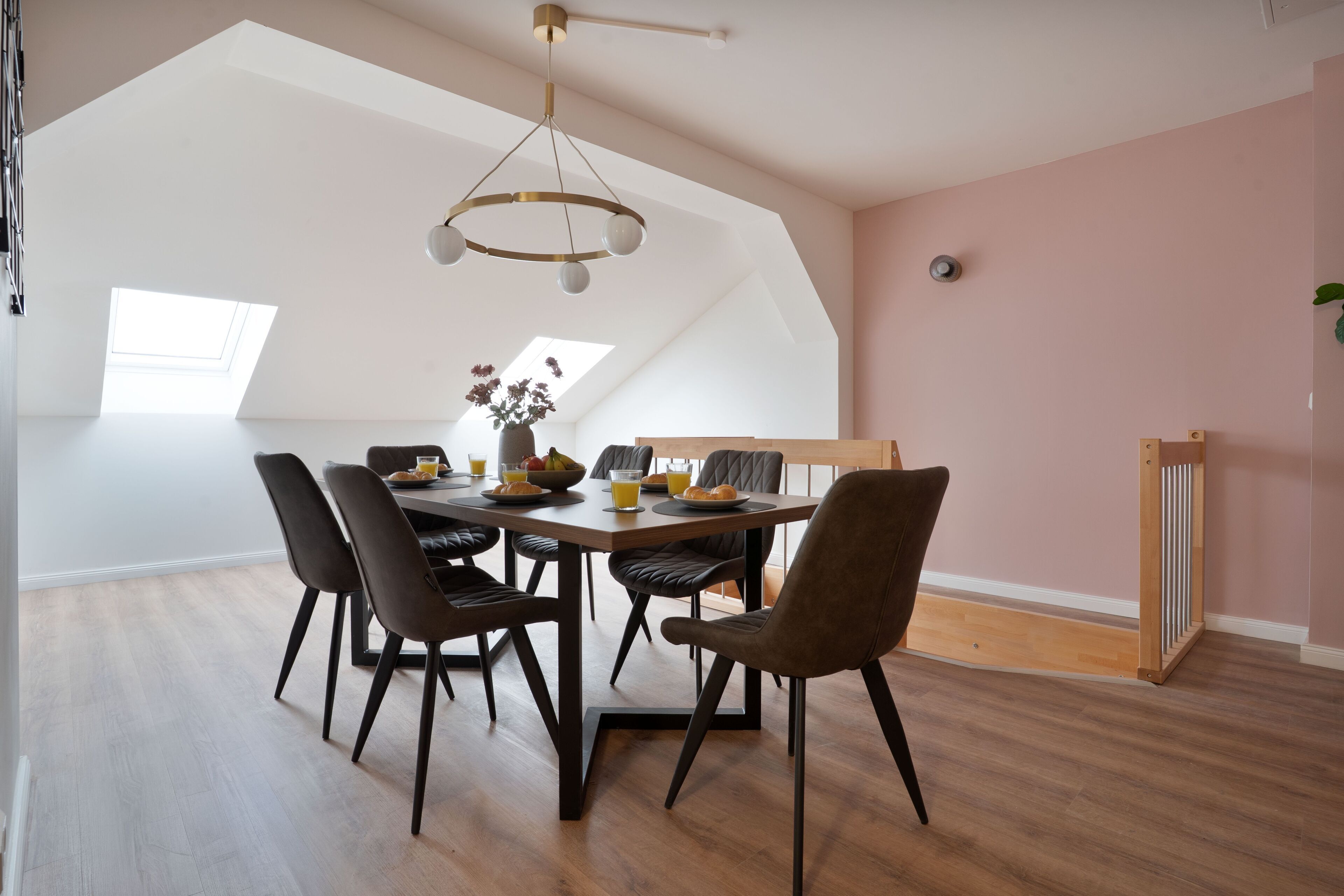 A dining area with a high ceiling, a skylight, and a modern chandelier.