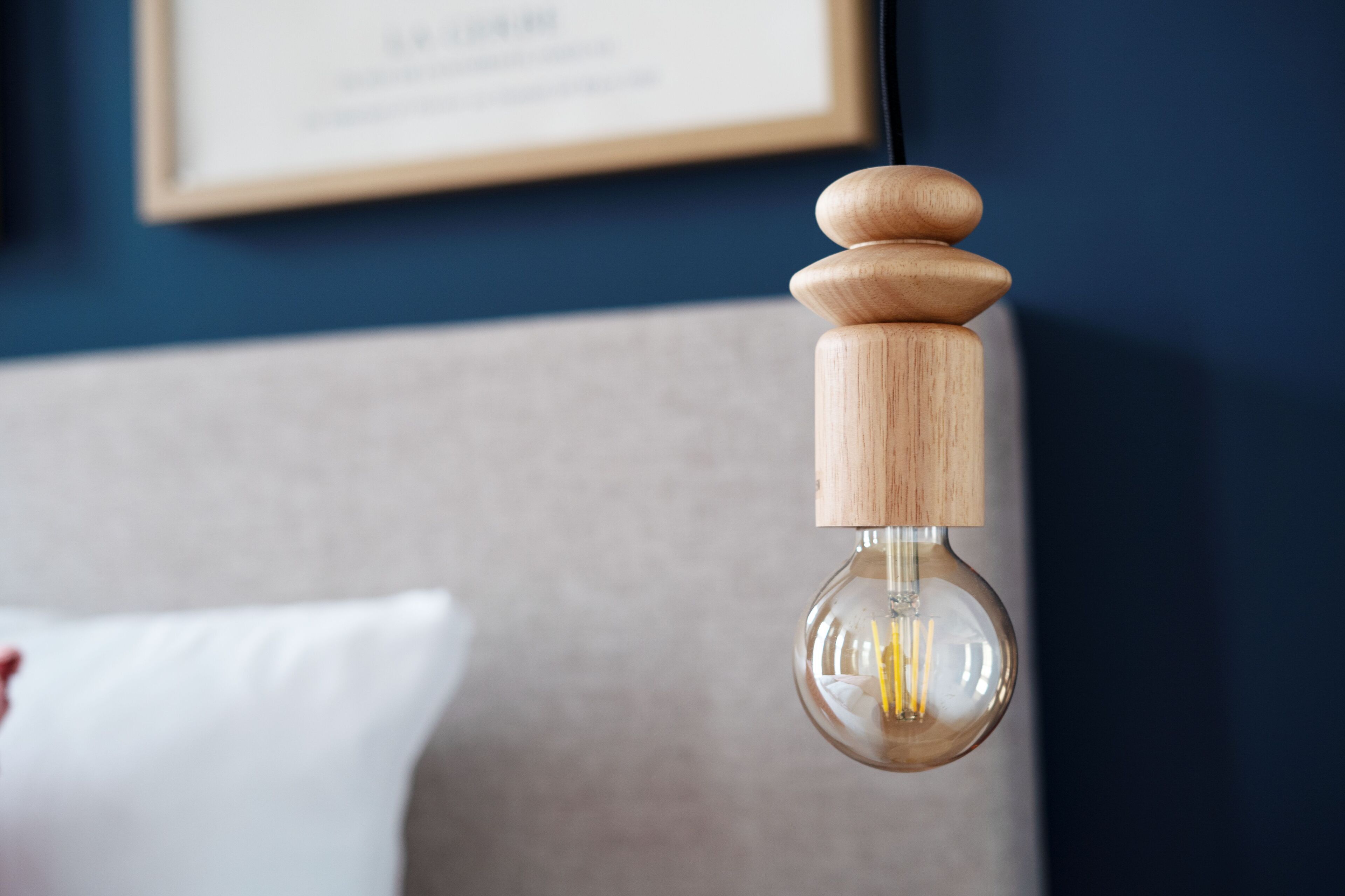 A hanging light bulb with a wooden base and a clear glass enclosure.