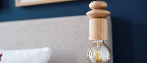 A hanging light bulb with a wooden base and a clear glass enclosure.
