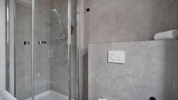 A modern bathroom with a glass-enclosed shower, a white sink, and a towel rack.