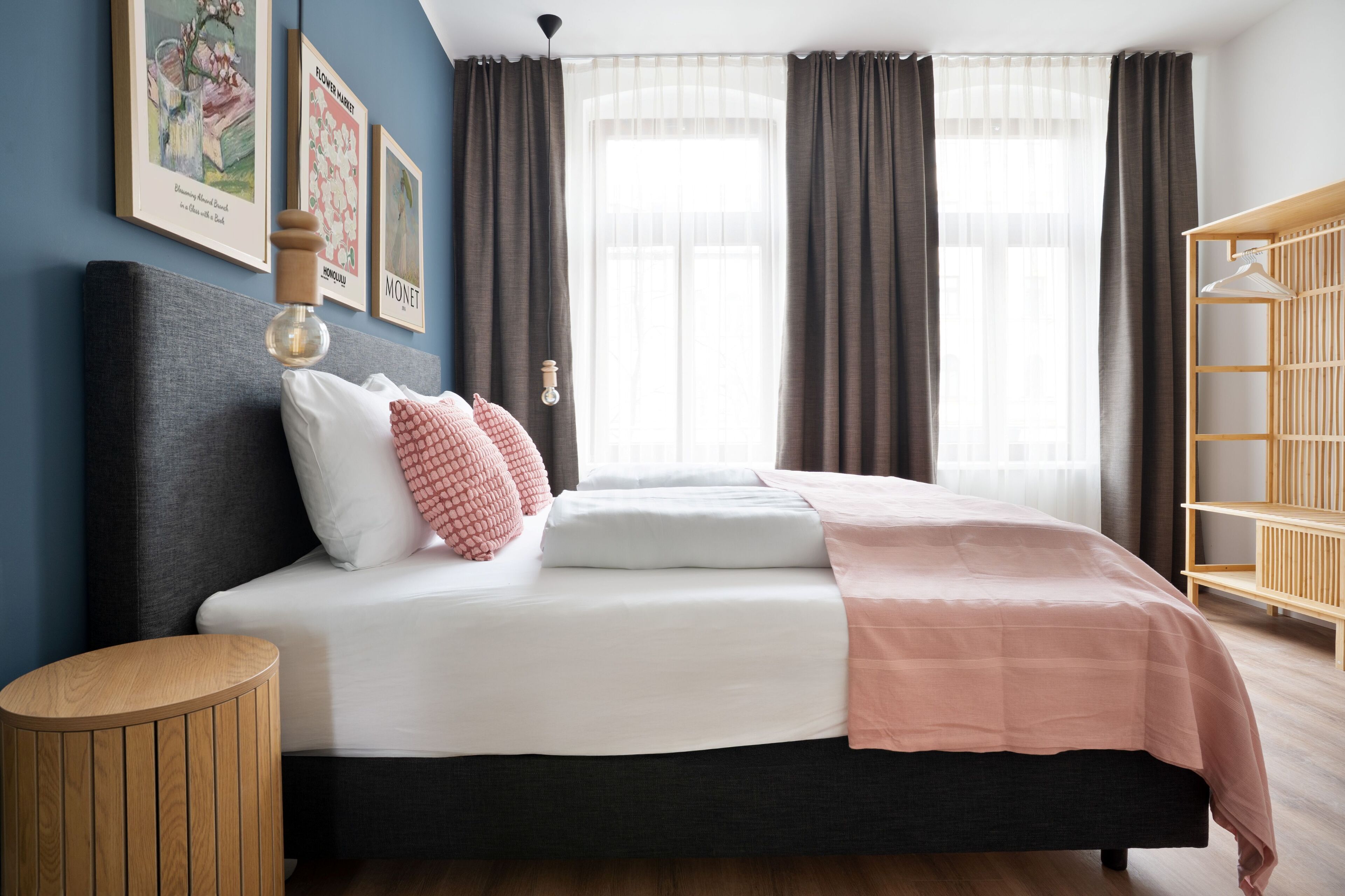 A modern bedroom with a bed, a bedside table, a wardrobe, and a window with curtains.