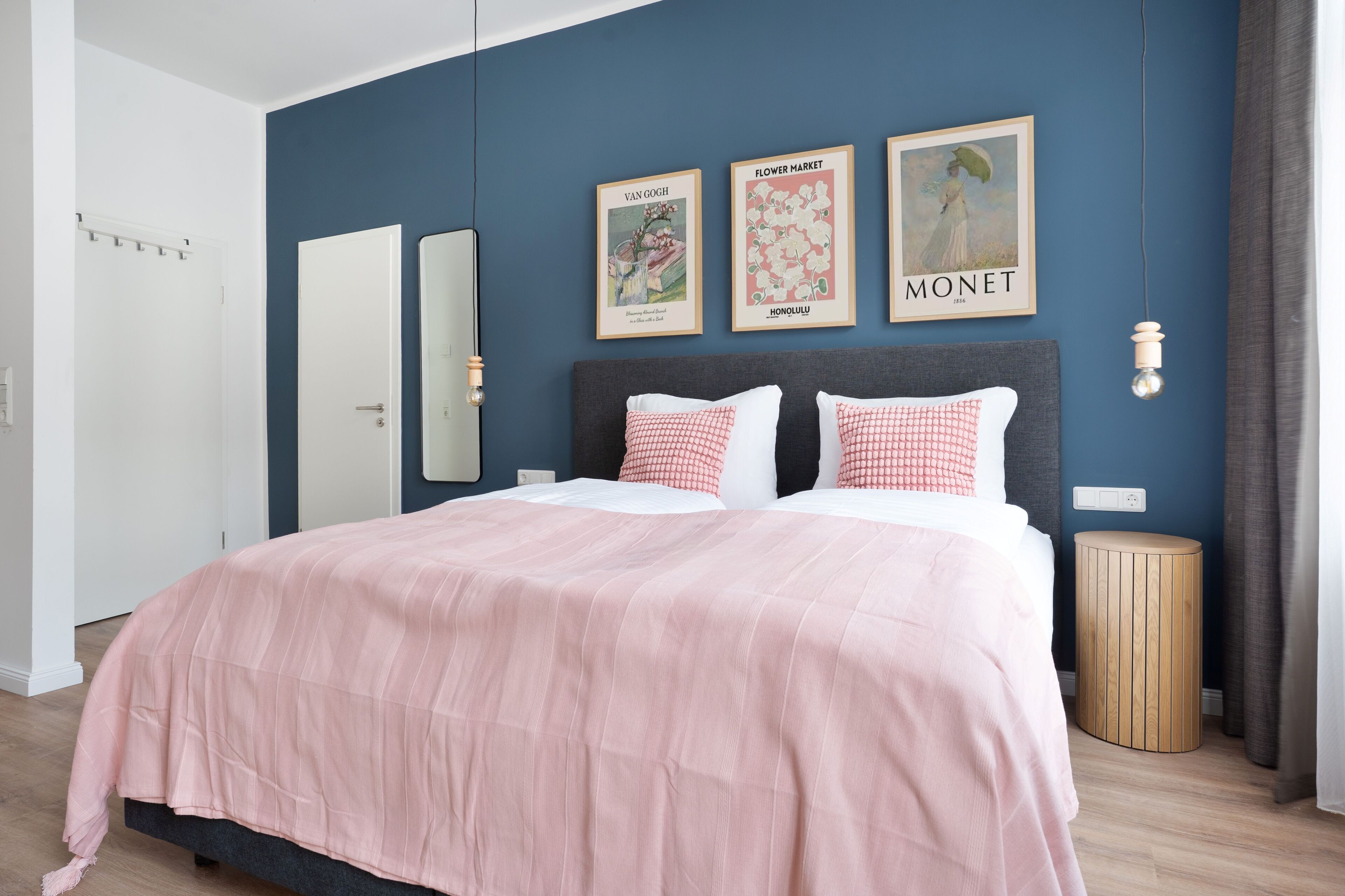 A bedroom with a bed, a bedside table, a mirror, and wall art.
