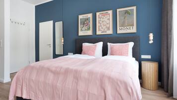 A bedroom with a bed, a bedside table, a mirror, and wall art.