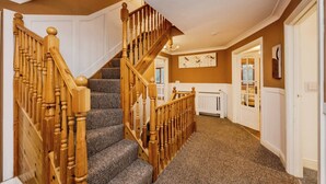 Un escalier avec des balustrades en bois et des marches recouvertes de moquette, menant à un palier.