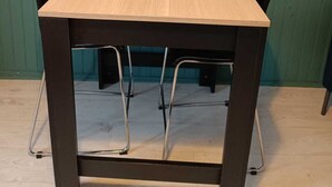 A table with a wooden top and black circular centerpieces, flanked by black chairs, against a teal wall with a mounted TV and a round mirror. - Studio historic center Périgueux (Périgueux)
