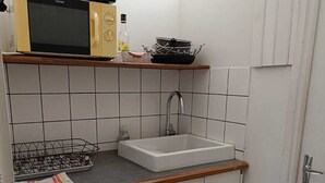 A compact kitchen with a microwave, sink, and washing machine. - Studio historic center Périgueux (Périgueux)