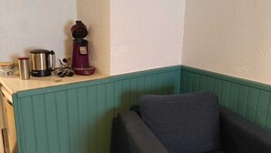 A small kitchenette with a coffee maker, kettle, and jar. There is a teal-colored bench and a dark-colored sofa. - Studio historic center Périgueux (Périgueux)