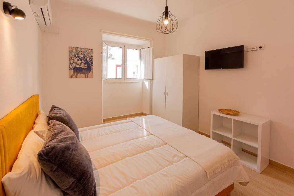 A bedroom with a bed, a wardrobe, a TV, and a window.
