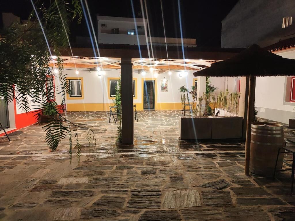 Un patio al aire libre con suelo de piedra, plantas en macetas y un banco de madera.