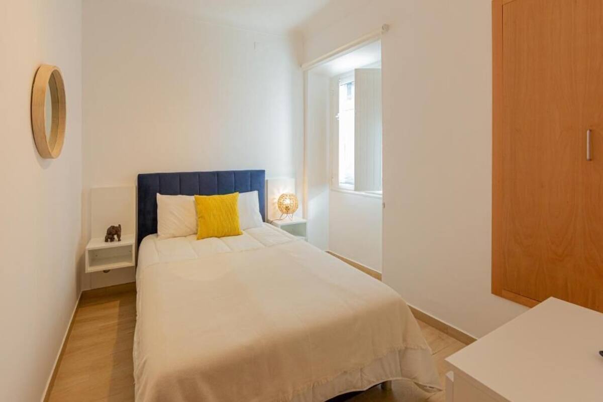 Un dormitorio con cama, mesita de noche y tocador.