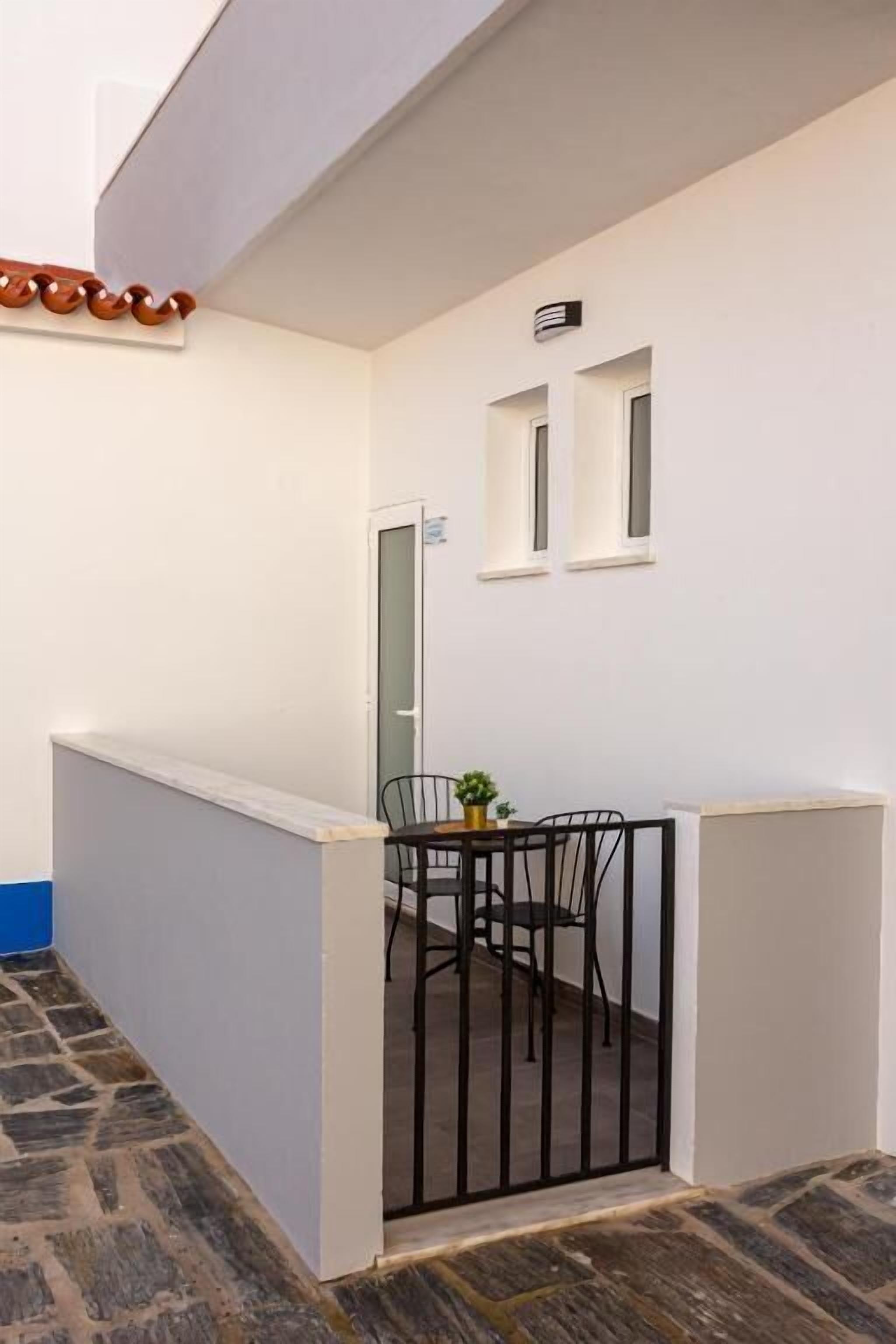 A small, enclosed balcony area with a table and chairs, a potted plant, and a door leading to an interior space.