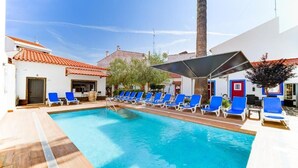 Ein Swimmingpool mit blauen Liegestühlen und einer Palme.