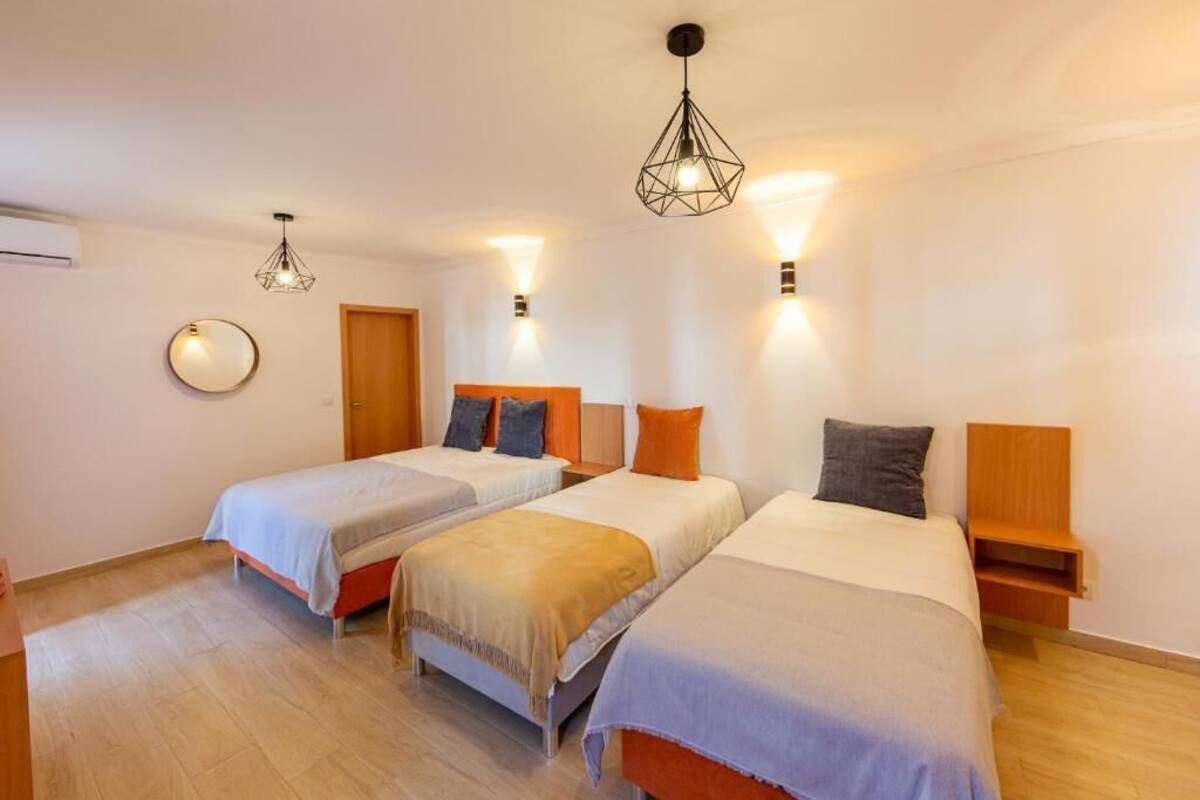 Una habitación de hotel con dos camas individuales, un espejo redondo y una puerta de madera.