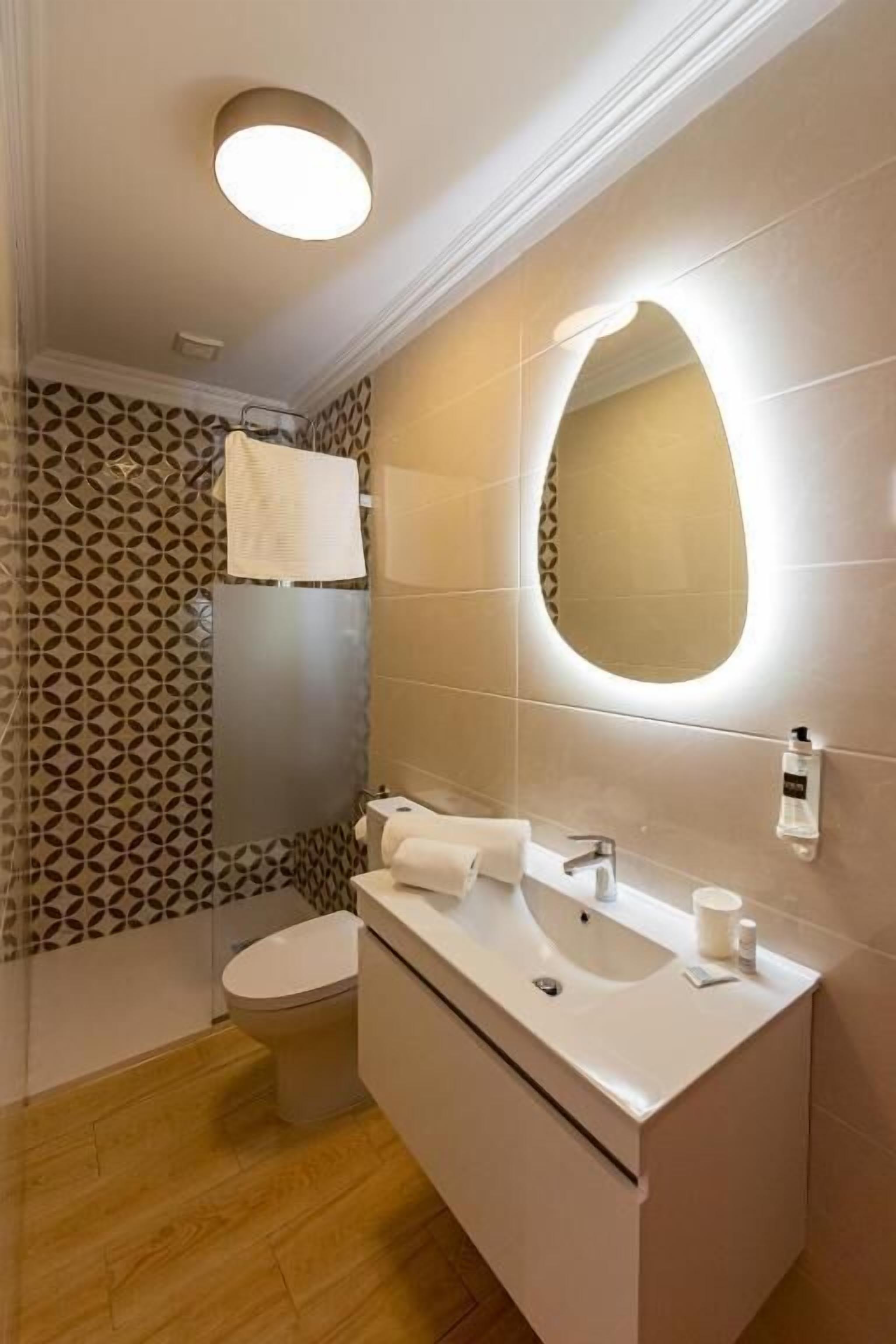 A modern bathroom with a toilet, sink, and mirror.