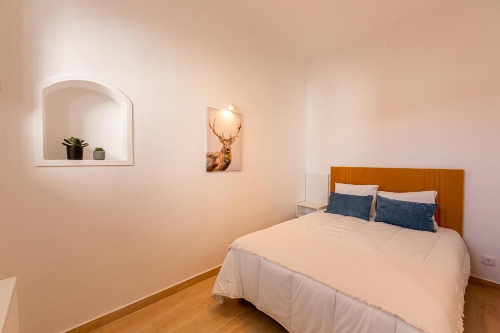 Une chambre à coucher comprenant un lit, une tête de lit, une étagère fixée au mur avec des plantes et un luminaire fixé au mur.