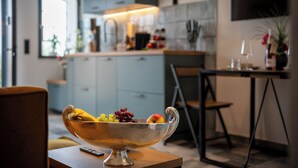 Eine moderne Küche mit Obstschale auf einem Tisch, einem Essbereich mit Stühlen und einer Kücheninsel mit Spüle und Arbeitsfläche.