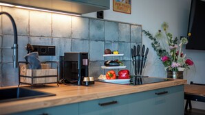 Een moderne keuken met een koffiezetapparaat, een presentatie van fruit en een messenblok op het aanrecht.